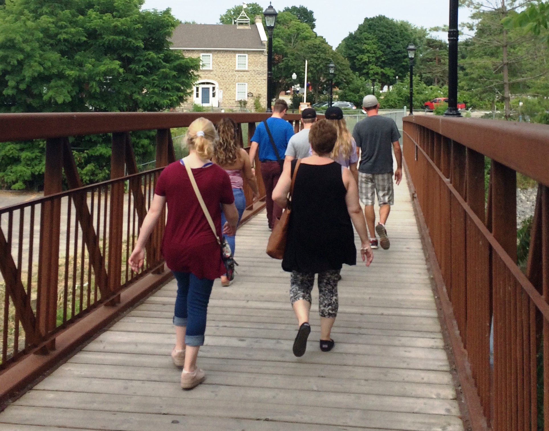 Group of people walking across a bridge towards an old building.